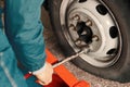 Man changes wheel of car in car service. Professional auto mechanic in overalls removes wheel from truck in garage Royalty Free Stock Photo