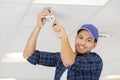 man changing ceiling light bulb