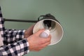 Man changing light bulb in lamp on greyish green background, closeup Royalty Free Stock Photo