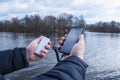 A man charges a smartphone with a power bank. The phone in hand is being charged with a portable charger against the backdrop of