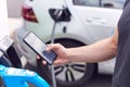 Man Charging Electric Vehicle With Cable Looking At App On Mobile Phone Royalty Free Stock Photo