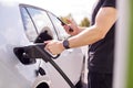 Man Charging Electric Vehicle With Cable Looking At App On Mobile Phone Royalty Free Stock Photo