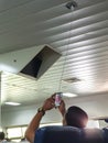 man charging his cell phone on public river transport with an electrical socket on the ceiling