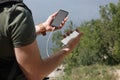 Man charging mobile phone with power bank on hill near river, closeup Royalty Free Stock Photo