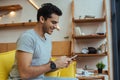 Man chatting on smartphone and smiling on sofa