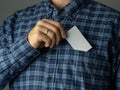 A man in a checked blue shirt tucks a business card into his pocket