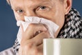 Man in a checkered scarf with big mug and tissue on blue background. Cold and flu illness relief Royalty Free Stock Photo