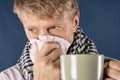 Man in a checkered scarf with big mug and tissue on blue background. Cold and flu illness relief Royalty Free Stock Photo