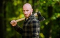 Man checkered shirt use axe. Brutal male in forest. Power and strength. Lumberjack carry ax. Bald woodsman. Harvest