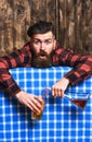 Man in checkered shirt on wooden background, blue tablecloth.