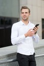 Man checking emails in morning urban background. Businessman send messages or texting with smartphone. Guy handsome