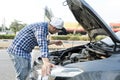 Man checking engine lube oil level under car hood, fix broken car on the street