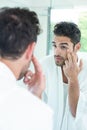 Man checking eyes in bathroom mirror