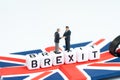 Man checking hand on cube block with alphabets building the word BREXIT on union jack UK flag with white copy space background Royalty Free Stock Photo