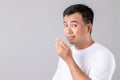 Man checking his breath with hand. Portrait asian man are sleepy in studio shot on grey background Royalty Free Stock Photo