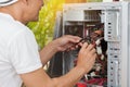 Man checking power signal of tower PC with meter probes of digital meter.