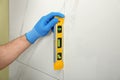 Man checking proper ceramic tile installation with level on wall. Royalty Free Stock Photo