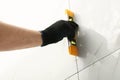 Man checking proper ceramic tile installation with level on wall, closeup. Royalty Free Stock Photo