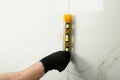 Man checking proper ceramic tile installation with level on wall, closeup. Royalty Free Stock Photo