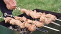 Man checks kebabs for readiness with a knife. Outdoor barbecue. Frying raw meat Royalty Free Stock Photo