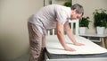 A man checks the stiffness of a new comfortable mattress.
