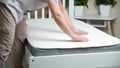 A man checks the stiffness of a new comfortable mattress.