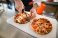 man chef accurate cuts pizza on cutting board into pieces with pizza cutter Royalty Free Stock Photo