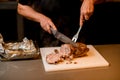 man chef cuts cooked fried meat on white cutting board. Royalty Free Stock Photo