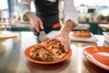 man chef gently takes piece of sliced pizza with metal spatula