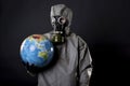 Man in a chemical protection suit and a gas mask. The guy is holding a model of the Earth, a globe. Royalty Free Stock Photo