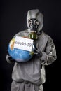 Man in a chemical protection suit and a gas mask. The guy is holding a model of the Earth, a globe. A placard with the Royalty Free Stock Photo