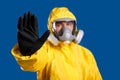 Man in chemical protective suit making stop gesture against background, focus on hand. Virus research Royalty Free Stock Photo