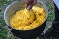 A man chews polenta in a cauldron