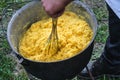 A man chews polenta in a cauldron