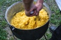 A man chews polenta in a cauldron