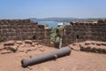 A man with a child near old cannon looking at the Indian ocean from the height of the fortress Cabo De Rama in India