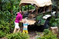 Man and child push car stuck in mud in jungle. Family pushing off road vehicle stuck in muddy dirt terrain in tropical forest. Royalty Free Stock Photo