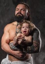 Sporty brutal man holds in arms a little baby