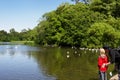 A man and a child standing by pond and looking at seagulls, duck Royalty Free Stock Photo