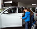 A man with a child is studying the interior of a new car through an open door