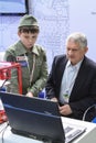 A man and a child are studying a program for working on a 3D printer