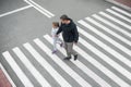 Man and child on a zebra crossing trespassing by crossing the street. In the summer on the street kid girl with her father in Royalty Free Stock Photo