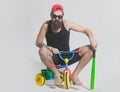 Man on a childrens bicycle. Bicycle rider, bearded angry man holds green baseball bat on bicycle toy.