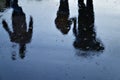 A man with a childs hand goes under an umbrella, reflection in the wet road, three silhouette figures Royalty Free Stock Photo