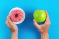 man chooses between an apple and a donut in his hands. Healthy food concept. Cropped view of male hands holding fresh