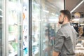 A man chooses frozen foods from shelves in a refrigerator in a supermarket. A man buys products in the store. Shopping in a Royalty Free Stock Photo