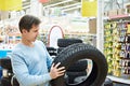 Man chooses winter studded tires for car in supermarket