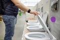 Man choosing a new toilet in construction store. Variety of sanitary ware in hardware shop