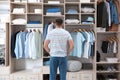 Man choosing outfit from large wardrobe closet with clothes, shoes and home stuff Royalty Free Stock Photo