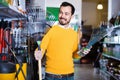 Man choosing various tools in garden equipment shop